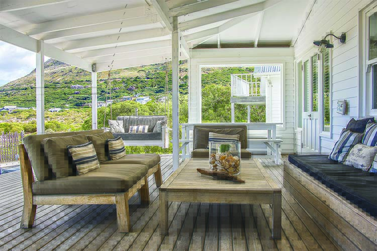 Cozy outdoor living space with wooden furniture, a coffee table, and scenic greenery visible through the windows.