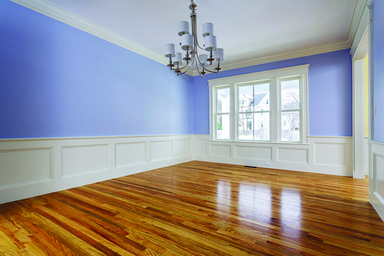 Spacious room with light purple walls, white wainscoting, hardwood floor, and a chandelier, featuring a large window.
